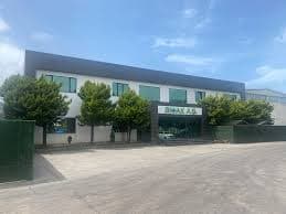 Modern white and grey industrial building with green trees and a BIMAK A.S. sign.